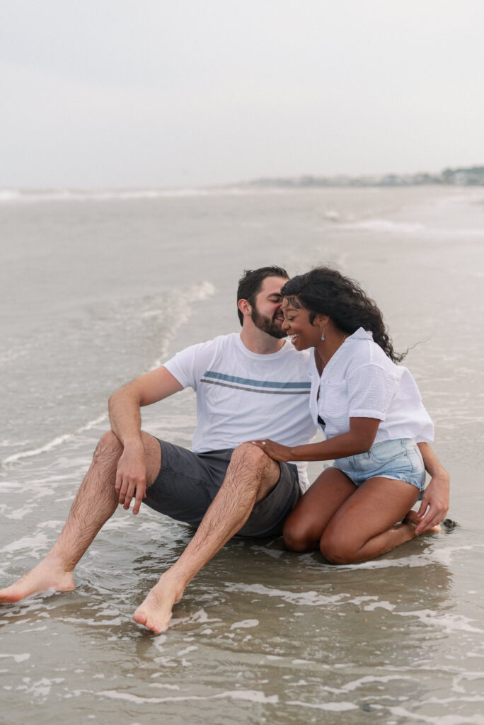 Couple sitting in the water laughing with each other on Isle of Palms