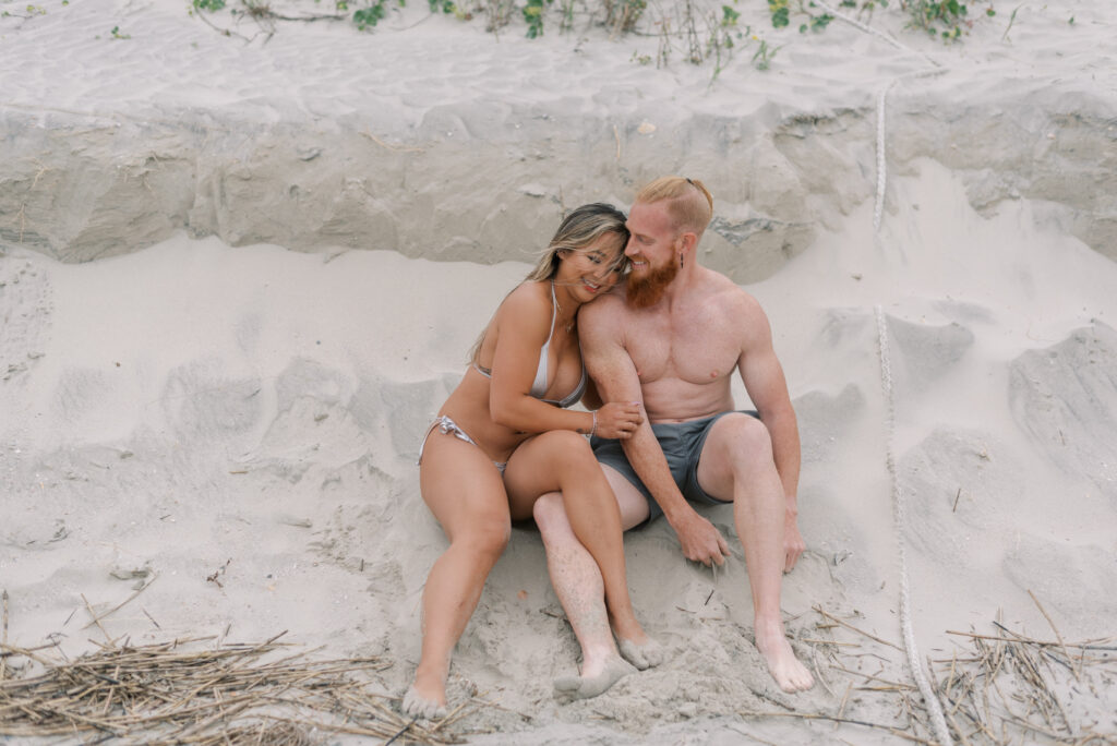 couple sitting in the sand against the dune at isle of palms beach